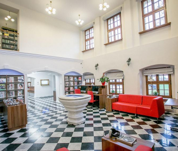 sala z biało czarnymi kafelkami na podłodze i czerwonymi kanapami